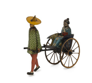 LEHMANN/MASUYAMA: wind-up lithographed tinplate toy with "Coolie" pulling spoke-wheeled rickshaw with an Asian Lady passenger in floral costume; umbrella missing, c.1930s, length 16cm, height 15cm.