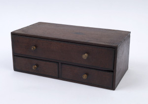 A miniature three drawer chest, mahogany with ebony trim and whalebone handles (one replaced), early 19th century, 12cm high, 32cm wide, 16cm deep