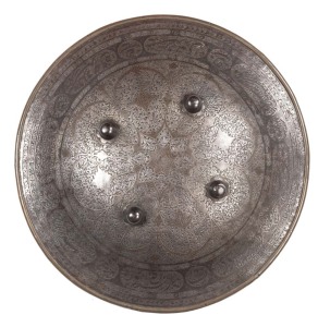 INDIAN STEEL CHISEL ENGRAVED SHIELD: with foliage, leaves & flowers, turned over rim & with 4 central bosses; 20" wide with faded red cloth backing; hand guard strapping missing; vg cond with blue/grey patina finish. C.1820