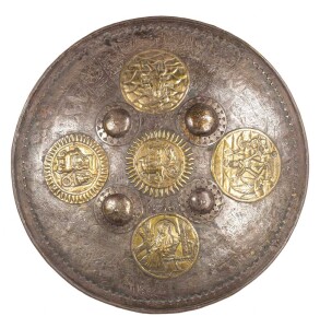 MIDDLE EASTERN METAL PARADE SHIELD: 24" in diameter with 4 central bosses & 5 brass plaques depicting entertainers, Sultan on a throne, chariots & armed deity; shield fully chisel engraved with depictions of importance; g. cond. 