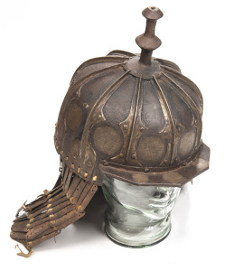 RARE SUMO-TIBETAN SIEGE TYPE IRON HELMET: domed skull formed of 10 overlapping embossed plates to form raised ribs, each plate having a silver inlaid mon type tailman to the bottom edge; the top fitted with a moulded baluster shaped finial; angular peak t