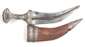 YEMANI JAMBIYA: 8¾" curved blade with raised central rib & light staining; plain silver mounted hilt with several small areas of ornate filigree work; g. brown leather over wood scabbard with a small hole near the chape; ornate silver locket with foliate 