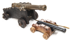 LOT OF 2 MODEL CANNONS: NO.1 A copy of an ENGLISH NAVAL CANNON: 18" brass barrel with VR & ROYAL CYPHER; 10 bore; complete with wooden Naval type carriage & wheels; g. cond. COPY of an ENGLISH NAVAL CANNON: 38 bore; 10½" steel barrel; blacked finish to b