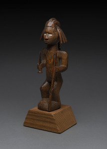 An African male fetish figure with gun and knife, carved wood, Babembe tribe, Congo area, on later wooden plinth, 28cm high overall