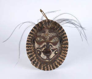 A ceremonial mask, tortoise shell, fibre, boar tusk, feather, shell and earth pigments, Papua New Guinea, ​28cm high