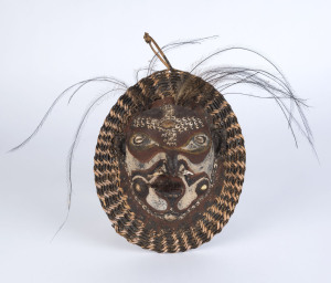 A ceremonial mask, tortoise shell, fibre, boar tusk, feather, shell and earth pigments, Papua New Guinea, 28cm high