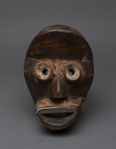 A Poro mask with round eyes, carved wood, vellum and earth, Dan tribe, Ivory Coast, ​24cm high