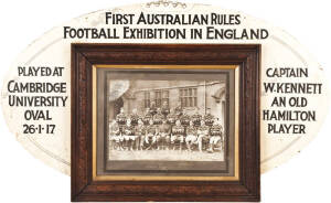 1917 PIONEER EXHIBITION GAME IN CAMBRIDGE: Team photograph, titled "Australian Football Team, Emmanuel College, Cambridge", framed & glazed, 60x51cm; mounted on large football-shaped backing board (overall 108x65cm), with text "First Australian Rules Foot