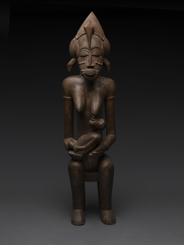 A seated female figure with pelican head dress and suckling baby, carved wood, Senufo tribe, Ivory Coast, ​87cm high