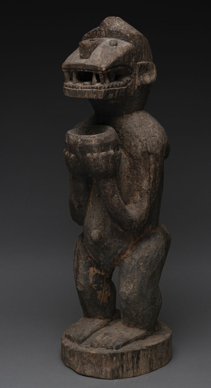 A rare standing monkey statue with offering bowl, carved wood with nature pigment finish, Baule tribe, Ivory Coast, 73cm high