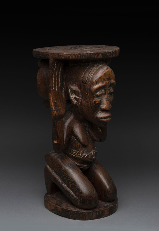 A Chieftain's stool in the long face style, carved wood with remains of piped clay, Baluba tribe, Southern Congo, ​44cm high