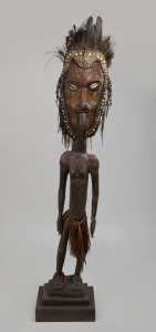 A standing male figure, carved wood, shell, feather, fibre and earth pigments, Papua New Guinea, on later wooden plinth, 165cm high overall.