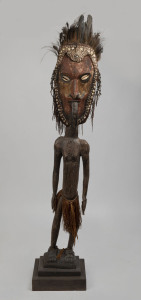 A standing male figure, carved wood, shell, feather, fibre and earth pigments, Papua New Guinea, on later wooden plinth, 165cm high overall.