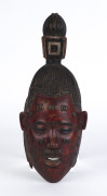 A mask with stylized top knot, carved wood with red and black painted finish, Guru tribe, Ivory Coast, ​40cm high