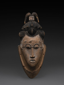 A mask with elaborate head dress and pointed teeth, carved wood and remains of polychrome finish, Guro tribe, Ivory Coast, 43cm high