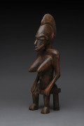 A seated female figure, carved wood with remains of red painted finish, Senufo tribe, Ivory Coast, ​48cm high
