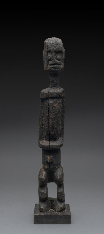 A standing male figure of elongated form, carved wood with black encrusted finish, Dogon tribe, Mali, on later wooden base, 49cm high