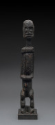 A standing male figure of elongated form, carved wood with black encrusted finish, Dogon tribe, Mali, on later wooden base, 49cm high