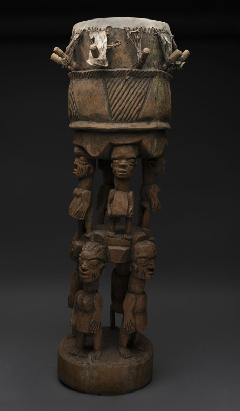 A ceremonial drum with eight standing figures, carved wood and hide, Yoruba tribe, Nigeria, 90cm high