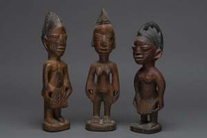 Three Ibegi figures, carved wood with paint and ochre finish, Yoruba tribe, Nigeria, 30cm, 28cm and 26cm high