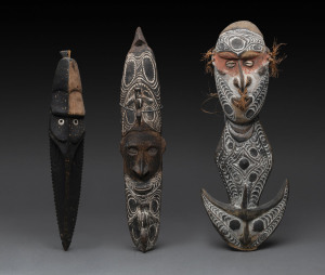 A food hook and two mask ornaments, carved wood, shell, fibre and earth pigments, Papua New Guinea, 49cm, 48cm and 43cm high