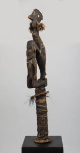 A flute stopper, carved wood, feather, fibre, shell and earth pigments, Papua New Guinea, ​139cm high