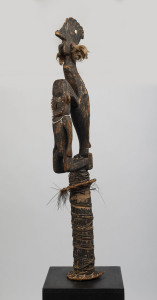 A flute stopper, carved wood, feather, fibre, shell and earth pigments, Papua New Guinea, 139cm high