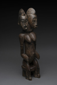 A double headed female seated figure, carved wood, cloth aand remains of painted finish, Senufo tribe, Ivory Coast, 54cm high