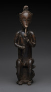 Seated male figure holdings his beard, carved wood and trade bead with remains of painted finish, Baule tribe, Ivory Coast, ​53cm high