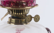 An antique oil lamp with brass base and column, clear glass font with cranberry prunts, brass double burner and chimney (later shade), has been electrified (wires cut), 68cm high - 2