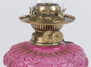An antique oil lamp with brass base and column, ruby glass font, brass double burner and chimney (later shade), has been electrified (wires cut), 68cm high - 2