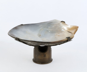 Scallop shell trench art ashtray, the clasps and base fashioned from a WWI artillery shell case, 7.5cm high, 15cm wide
