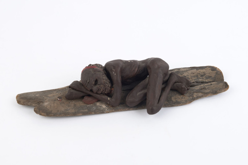 P. HOLMES pottery figure of and Aboriginal man mounted on a wooden base, signed P. Holmes", 28cm long