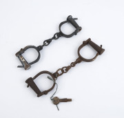Two sets of iron manacles, one with key, 20th century, the larger 31cm wide