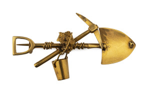 An Australian gold miner's brooch, crossed pick and shovel with hanging bucket, nugget specimen and entwined rope, 19th century, 4.5cm wide, 3.2 grams