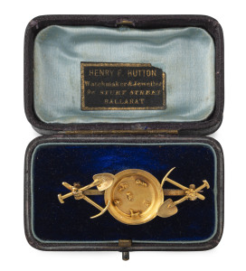 A rare Australian gold miner's brooch, gold pan with nuggets flanked by picks and shovels on each shoulder, housed in a period box marked "HENRY F. HUTTON WATCHMAKER & JEWELLER, STURT STREET BALLARAT", 19th century, rare. 5.5cm wide, 4.5 grams
