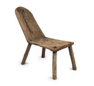 A rare and primitive Australian chair hewn from a single slab of eucalypt with stick legs, mid 19th century. Most likely central Victorian goldfields origin. Few examples of this type of chair or stool construction survive today. This piece with its unusual lounging posture and the addition of the bushman's antique butterfly restoration to the back make it one of the finest examples seen in our rooms. 94cm high, 43cm wide, 130cm deep