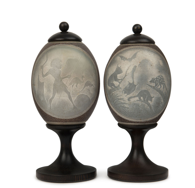 A pair of carved emu eggs with Aboriginal hunting scene and native animals, later turned wooden stands, late 19th century, ​21cm high