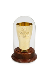 A CARLTON DRAUGHT BEER GLASS IN 18CT GOLD by HARDY BROTHERS JEWELLERS, 18cm high, the top measures 10.5cm diameter, the base measures 6.7cm diameter, weight 2066gms. Engraved on front "SINCE 1864 CARLTON DRAFT Brewery Fresh". Presented on a custom made wooden base under a glass dome.
