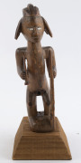 An African male fetish figure with gun and knife, carved wood, Babembe tribe, Congo area, on later wooden plinth, 28cm high overall - 2