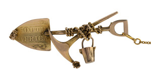 A South African gold miner's brooch with crossed pick and shovel, rope and bucket, stamped "9ct", ​5cm wide, 4.9 grams