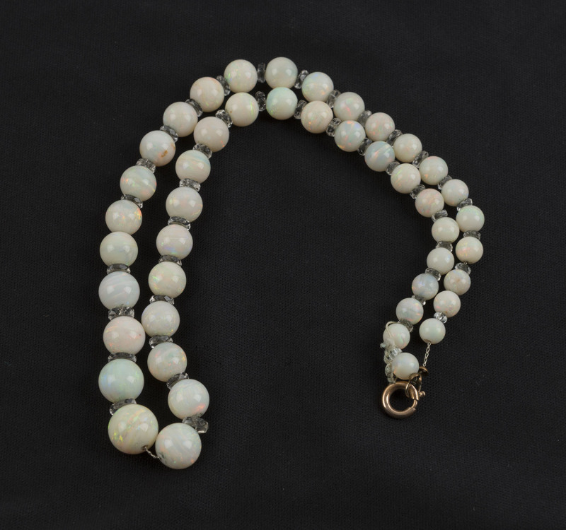 A vintage graduated opal and crystal bead necklace with rose gold plated clasp, early 20th century, each bead turned from solid Coober Pedy white opal. Formerly the property of DAME MARY COOK. Requires restringing. 44cm long. PROVENANCE: The Cook family