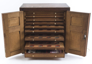 Coins - World : Wooden Coin Cabinet with 10 shallow drawers and deeper drawer at base, usually with 10 to 12 items per drawer with a respresentantive array of world coins, the deeper drawer at base with probably the best contents including 6 Roman coins (one an early forgery) including silver Denarius of Faustina and a Follis of Maxentius; also Austria 1780 Maria Theresa silver thaler, GB 1887 Crown, WWI brass Lusitania medal, plus a few other medallions,