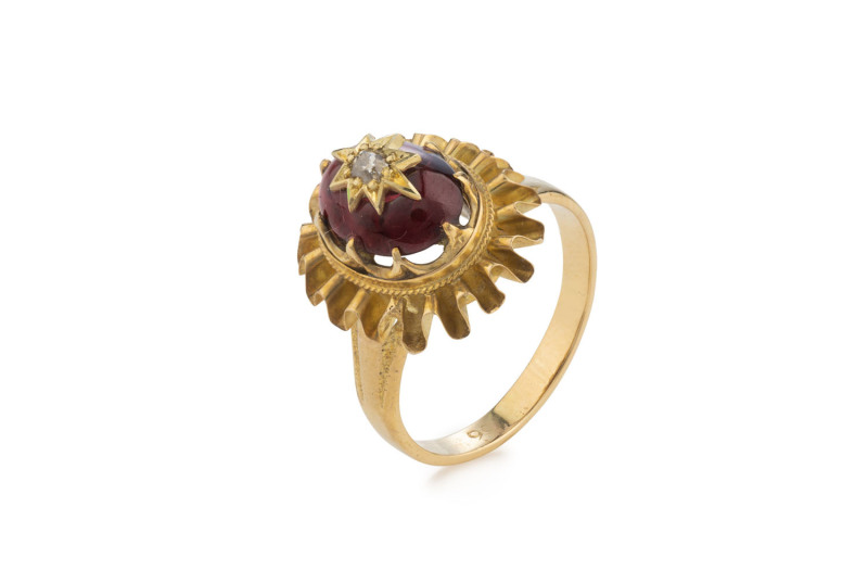 An antique 15ct yellow gold ring set with a large cabochon garnet adorned with a central diamond set in gold star, 19th century,