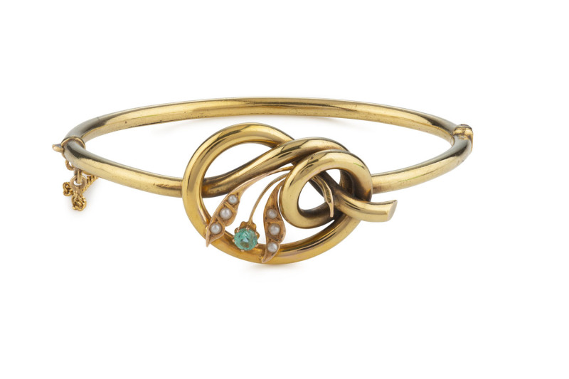 An antique 15ct gold bangle with love knot set with emerald and seed pearls, 19th century, ​6cm wide, 9.2 grams total