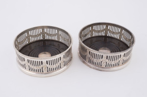 A pair of English wine bottle coasters, silver plate with bakelite bases, 20th century, 4cm high, 11cm diameter