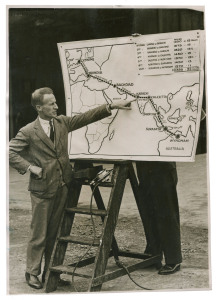 KINGSFORD SMITH'S RECORD ENGLAND - AUSTRALIA SOLO FLIGHT: 4 October 1933 original Dutch press photo with affixed details: "Sir Charles Kingsford Smith studying a map of the route he will take before leaving Heston Aerodrome today." The plane was a Perciva