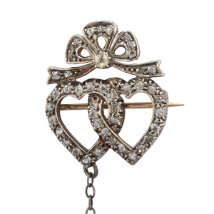 An antique double heart and bow brooch, pave set with diamonds in white and yellow gold, circa 1900, ​2.5cm high
