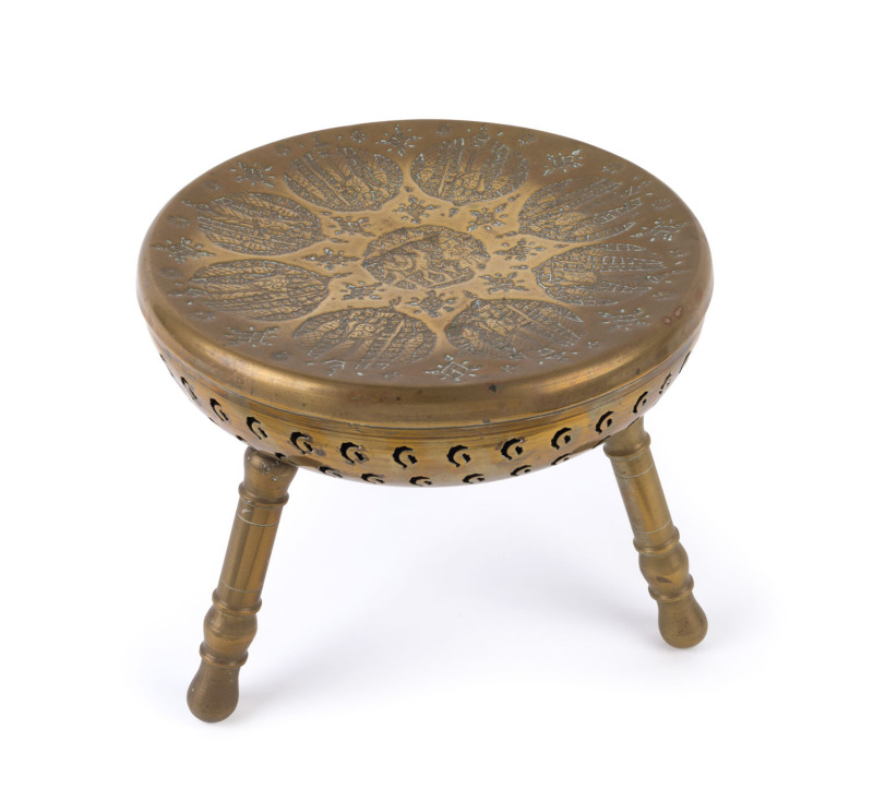 A Persian brass three legged stool with repoussé decorated top, 19th century, 30cm high, 34cm diameter