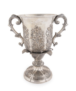 A Chinese Export Silver two-handled presentation cup, with embossed flowers and raised on a shaped circular base with a band of acanthus leaves. By CUTSHING, 8 New China Street, Canton, circa 1853, 26.5cm high, 1630gms.